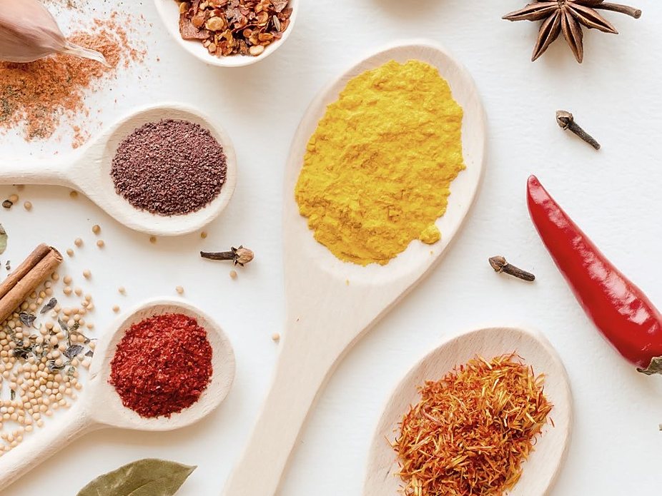 Ground and whole spices on wooden spoons