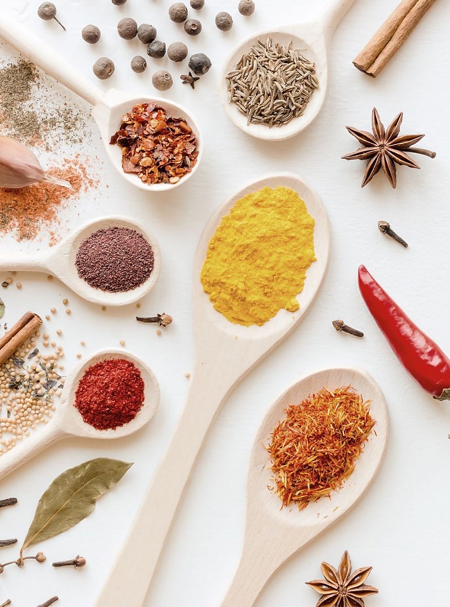 Whole and ground spices on wooden spoons